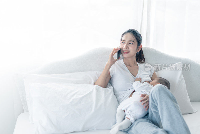 Single busy mother feeding to baby while busy with call.  Newborn baby being breastfed by mother.